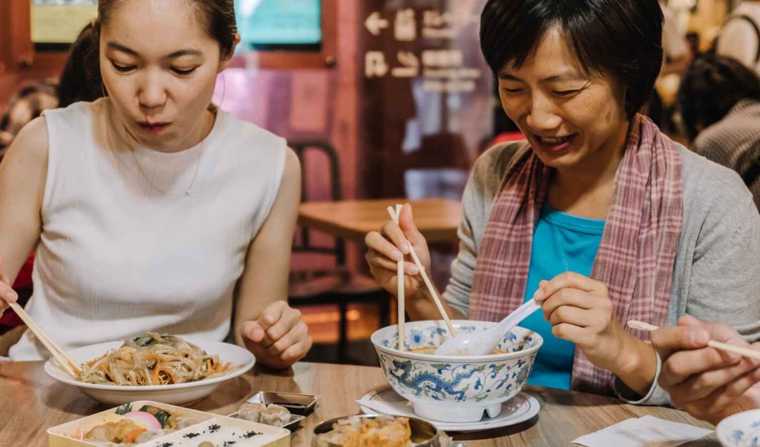 Three people eating at a restaurant table with noodles in Yokohama