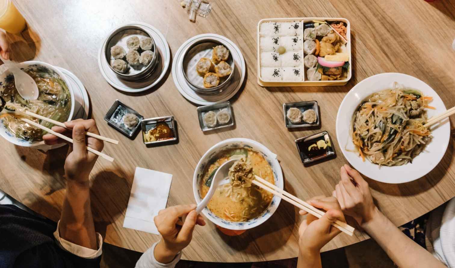 Top view of a wooden table with assorted Asian dishes in Yokohama