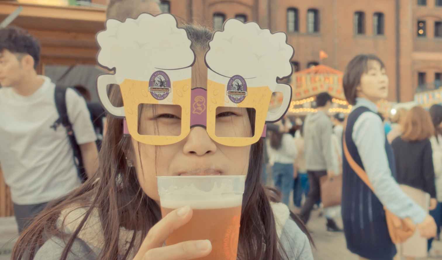 Person wearing novelty glasses holds a drink at Yokohama Red Brick Warehouse.