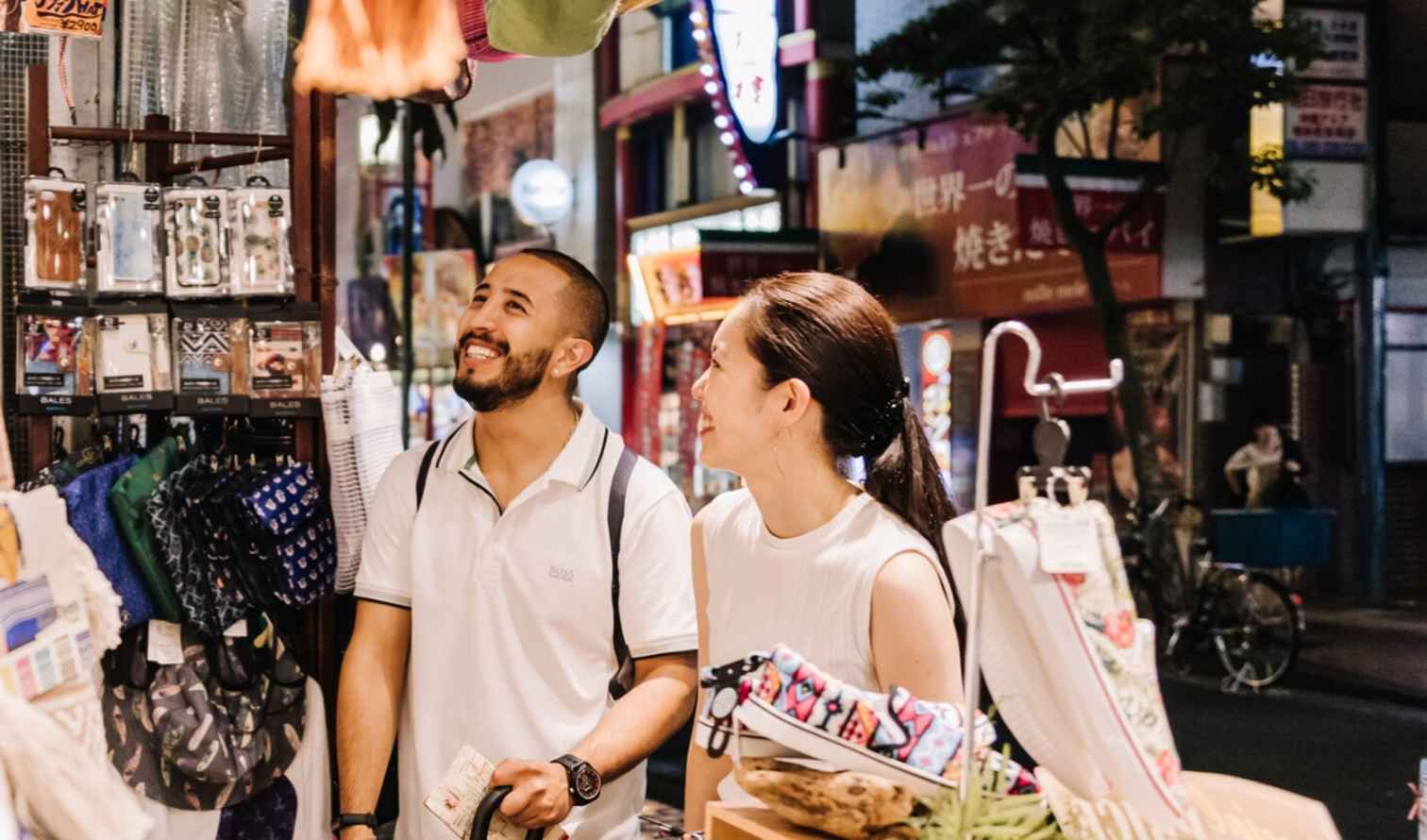 Two people browsing a street market in Japan at night in Yokohama