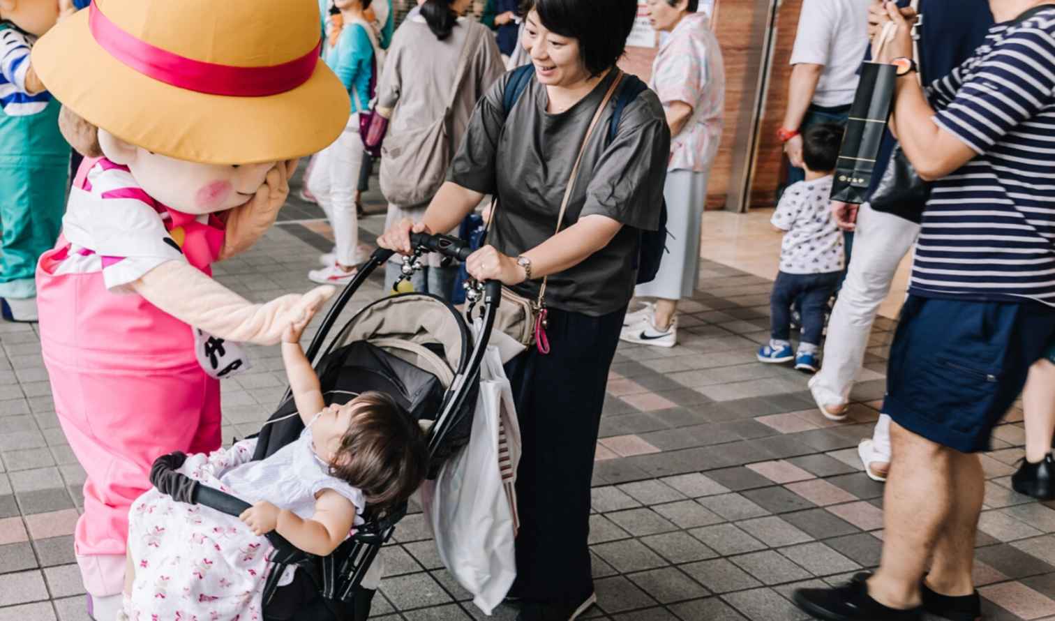 People gather around a mascot character at a public venue in Yokohama