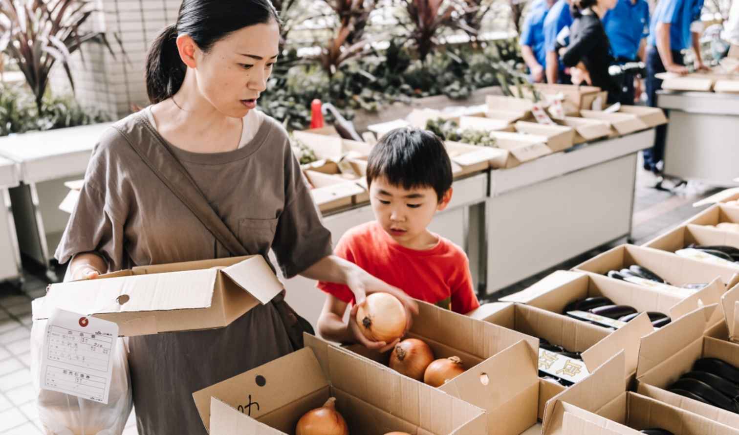 A woman and child choose onions at a market stall in Yokohama