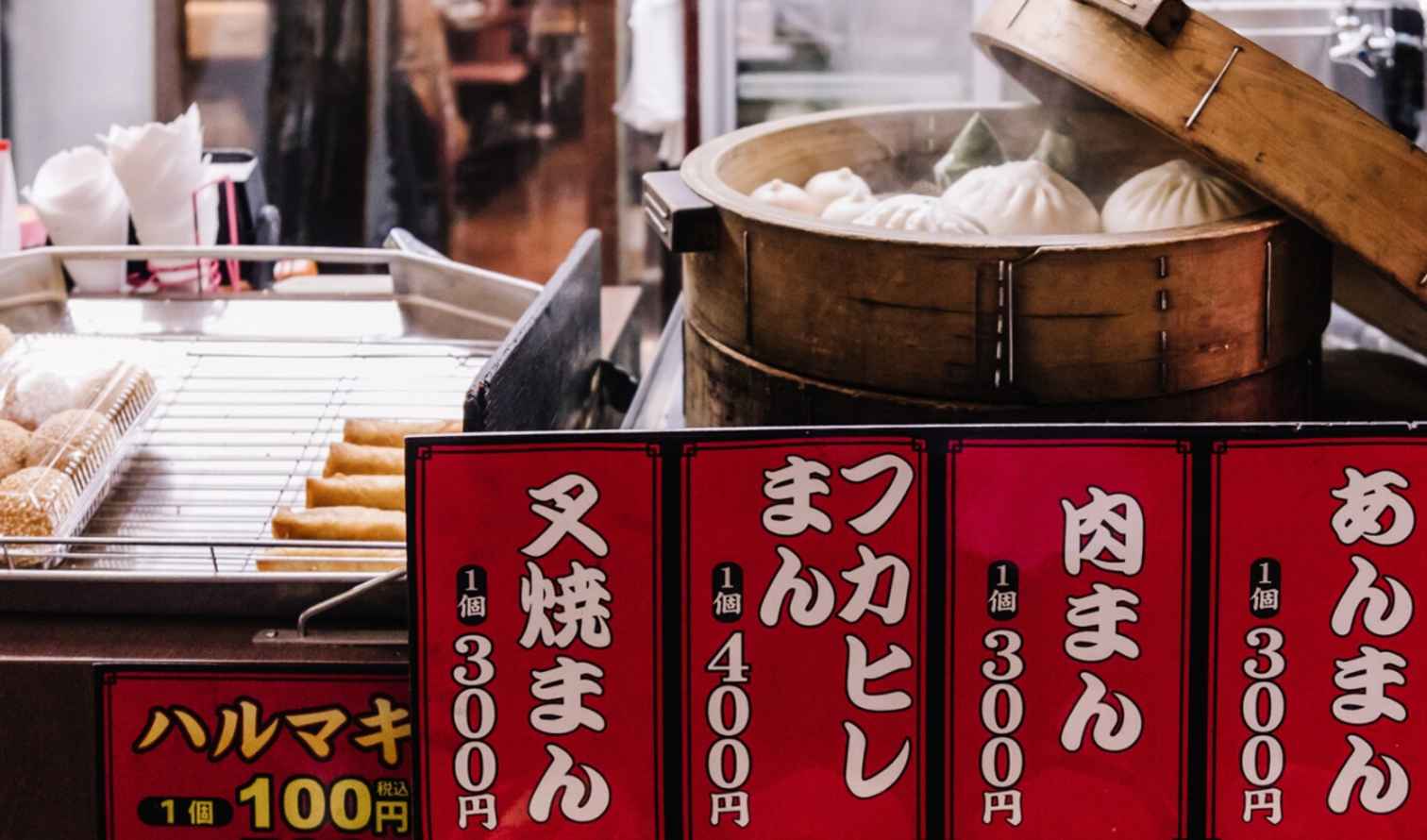 Close-up of various steamed buns with Japanese price tags at a food market in Yokohama