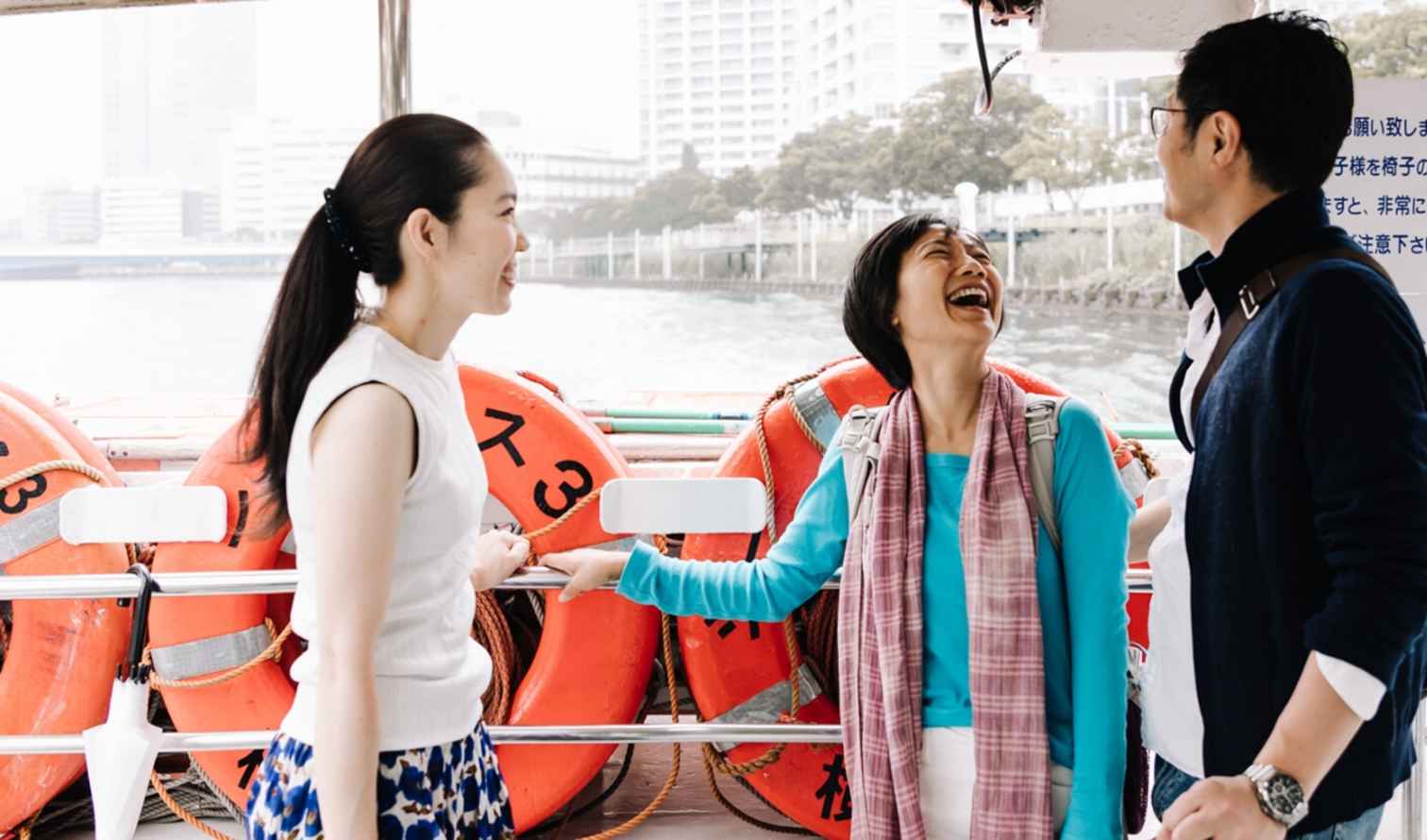 Group of three on a ferry in Yokohama with life rings visible.
