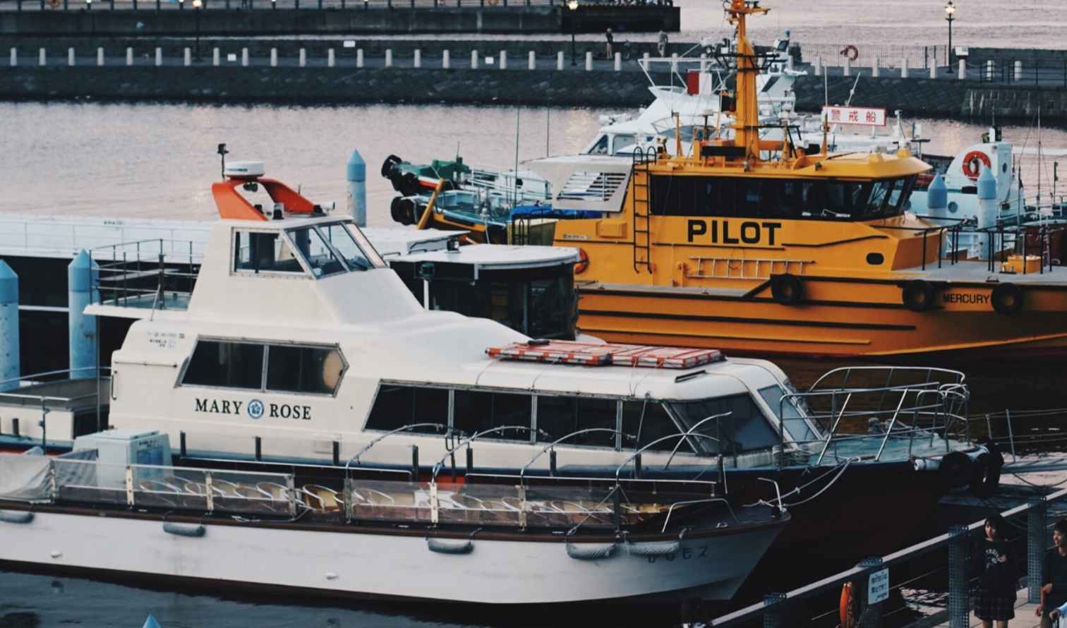 Boats docked at Yokohama Harbor in Japan with people walking nearby.
