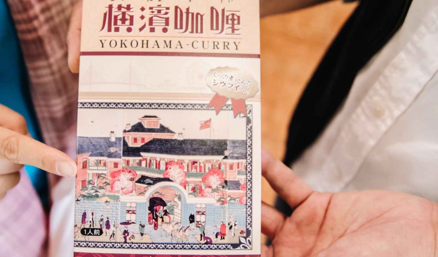 Two people holding a box of Yokohama curry.