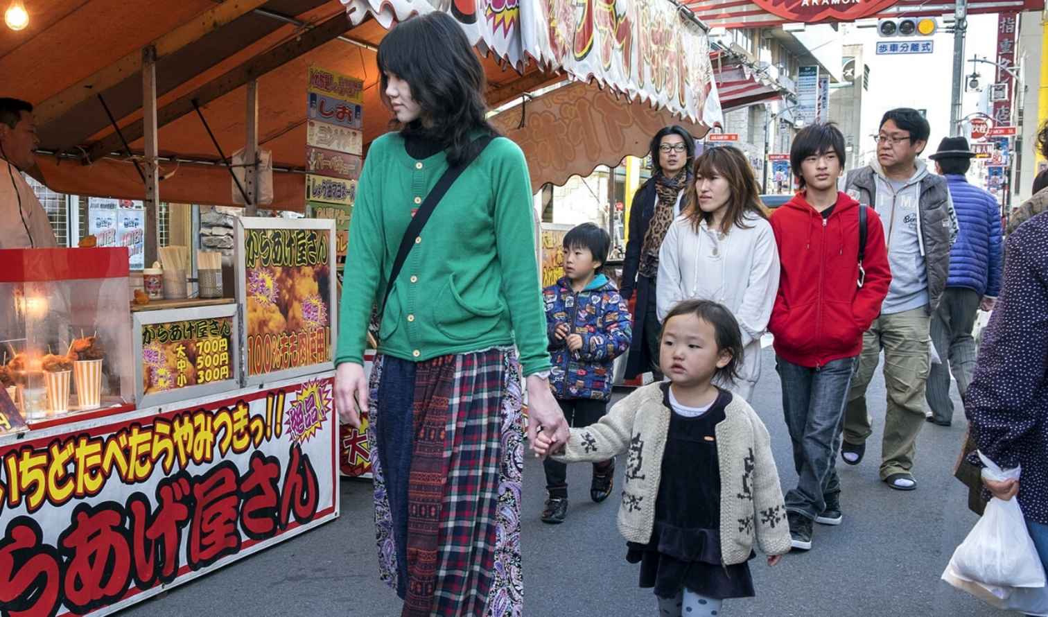 A woman and child walk past a food stall in Ameyoko market, Nagoya.