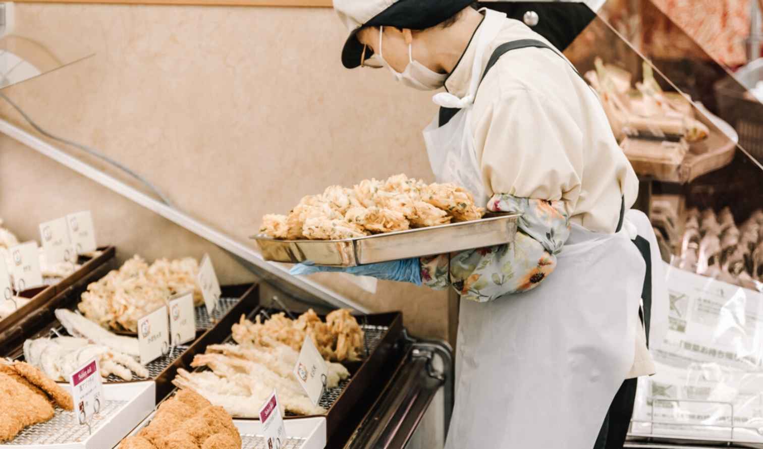 Worker placing tempura on a tray at a market food section in Nagoya