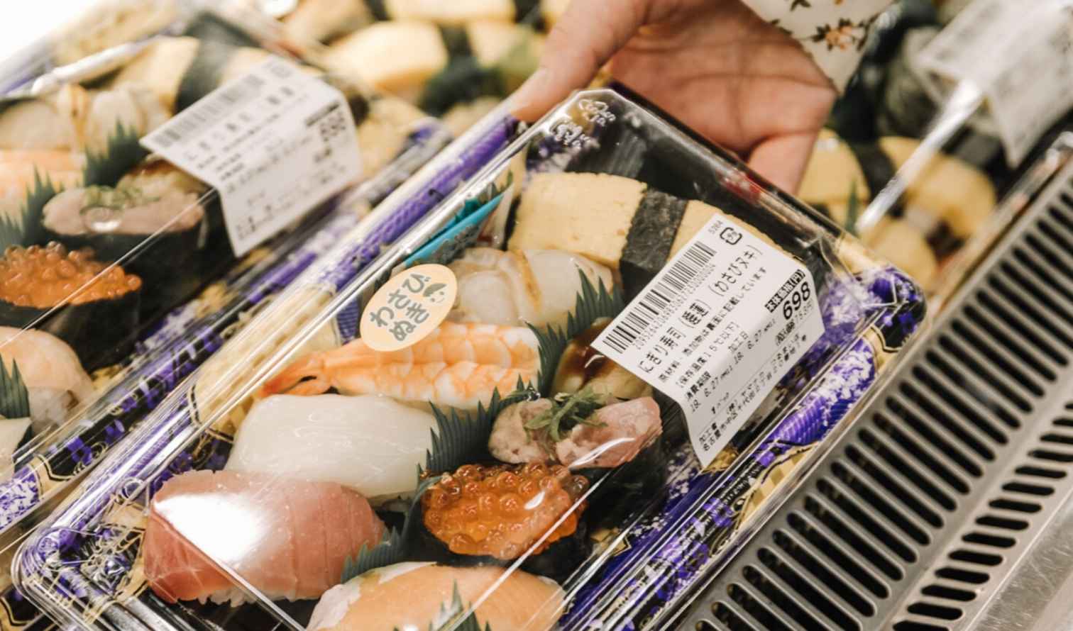 Hand reaching for packaged sushi in a grocery store in Nagoya