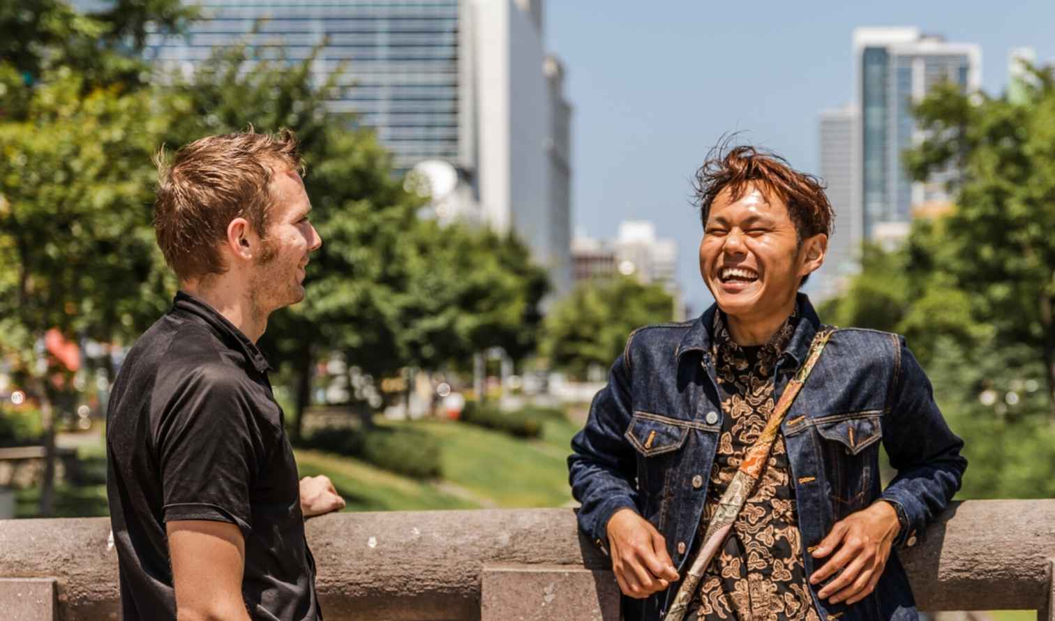 Three people talking near a stone railing in a city park in Sapporo