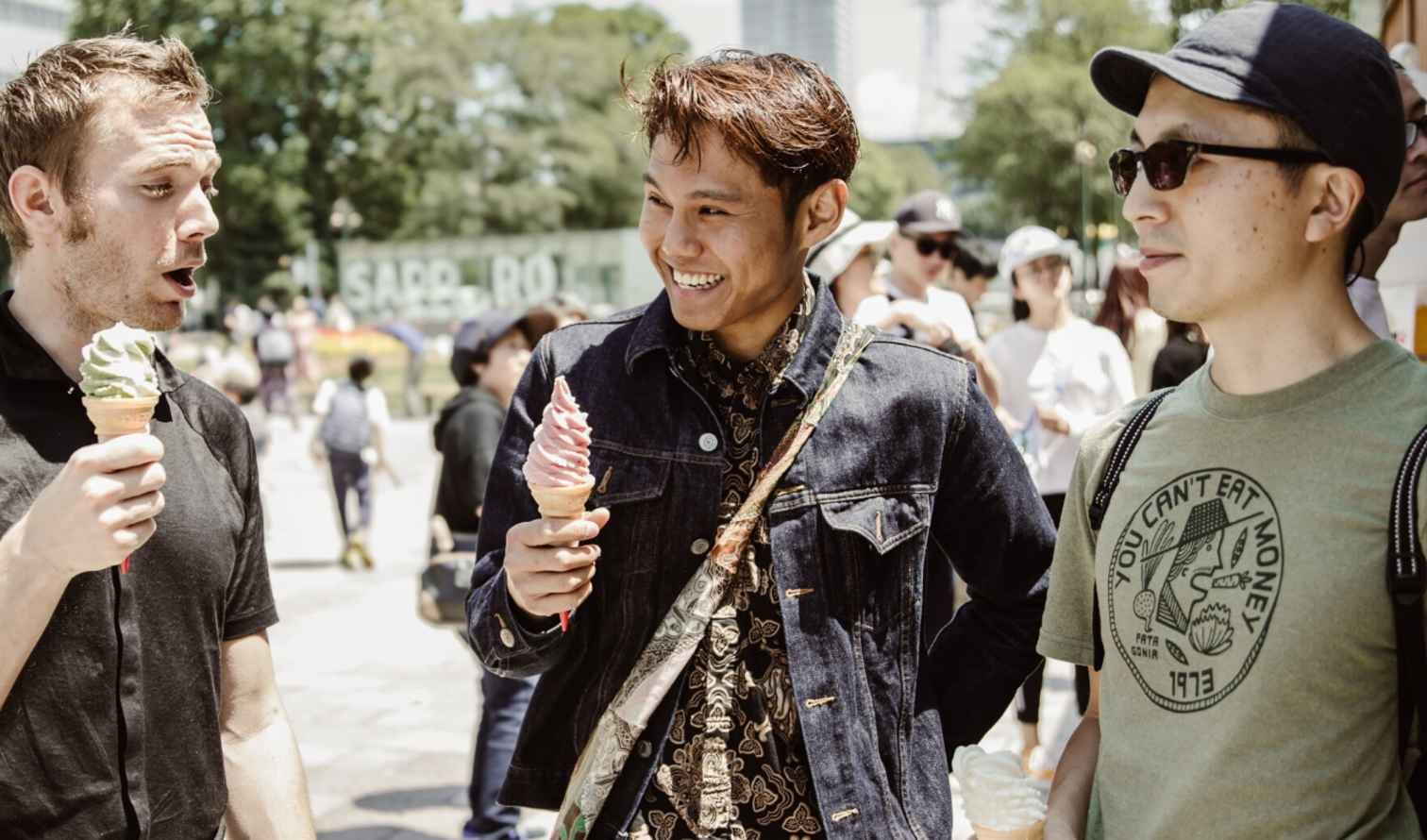Three people holding ice cream cones in a park in Sapporo