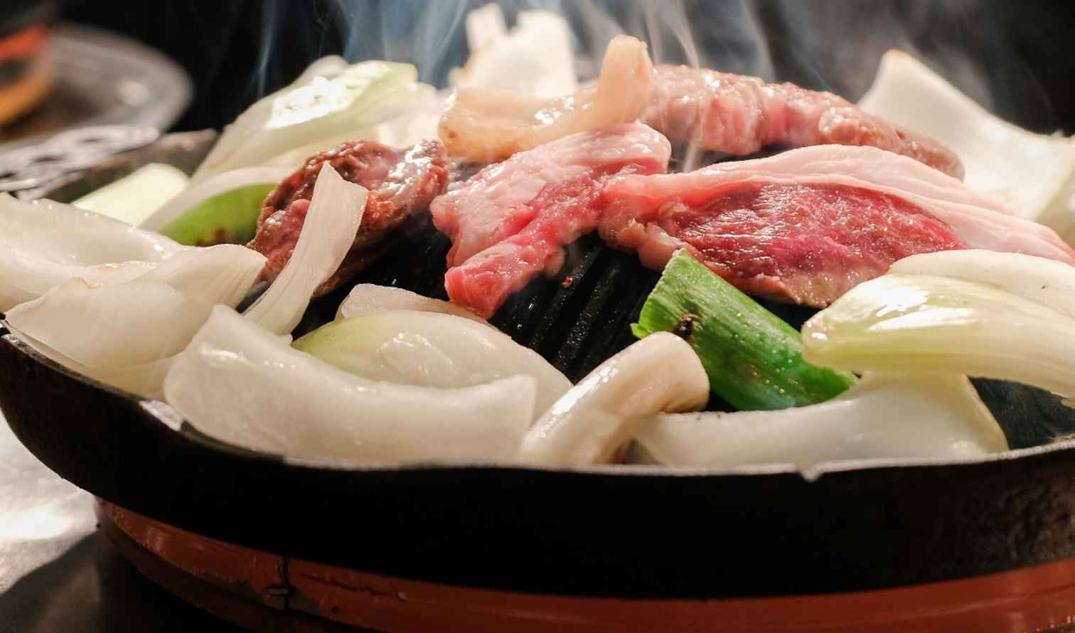 Grilled meat and onions cooking on a tabletop barbecue grill in Sapporo