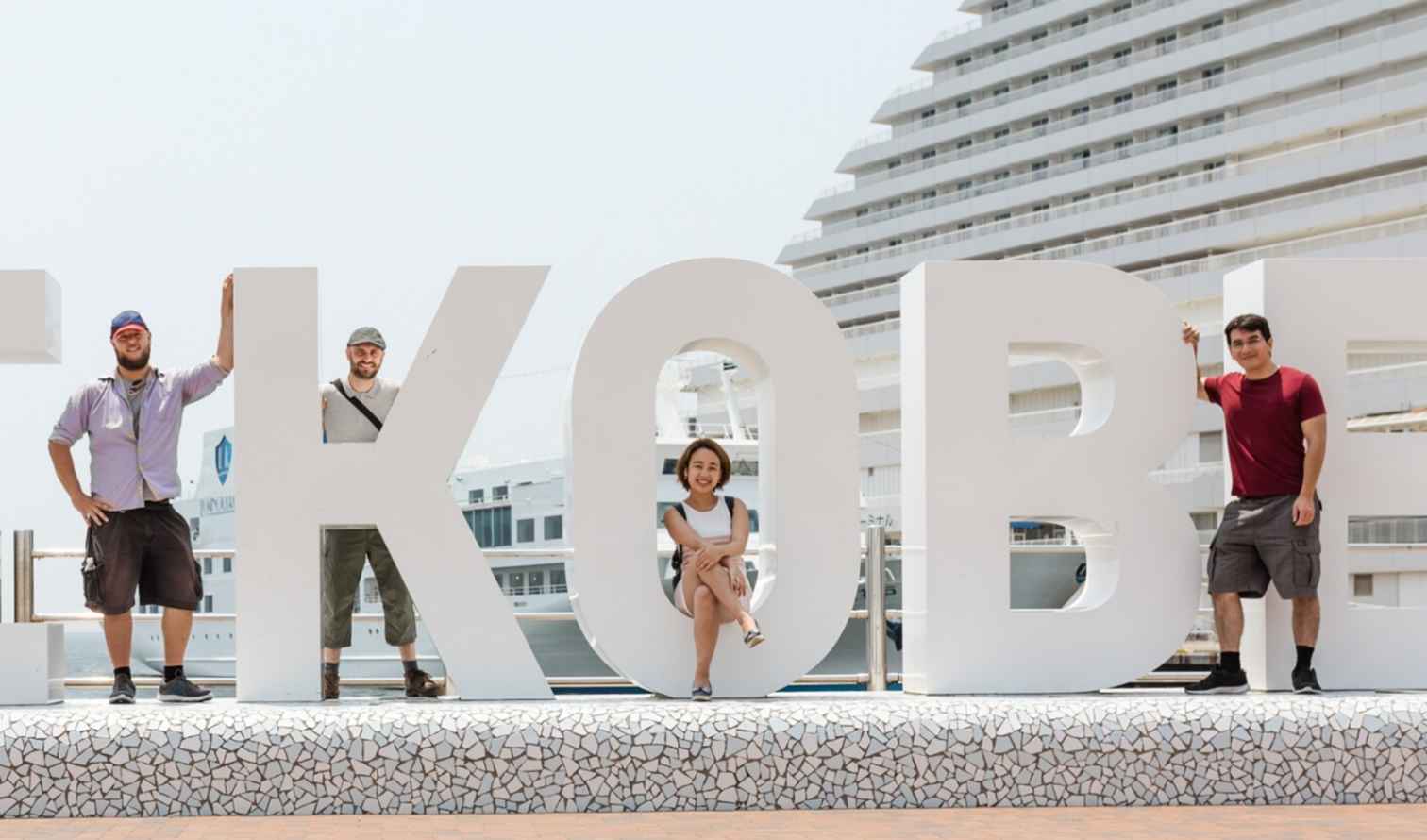 Five people standing with the 'BE KOBE' sign in Kobe, Japan.