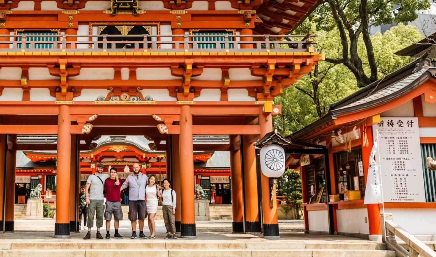 Japanese shrine entrance with lanterns and a visiting group in front in Kobe
