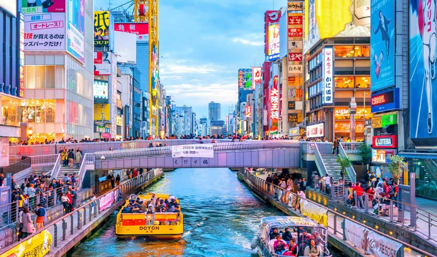 Dotonbori Canal with boats and people on the bridge in Osaka, Japan.