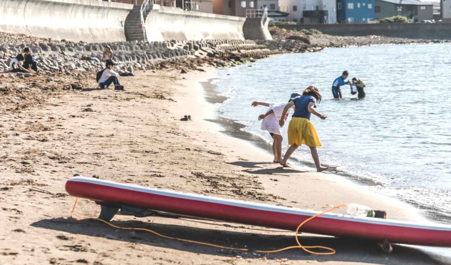 Children playing in the sand near a seaside residential area in Sapporo