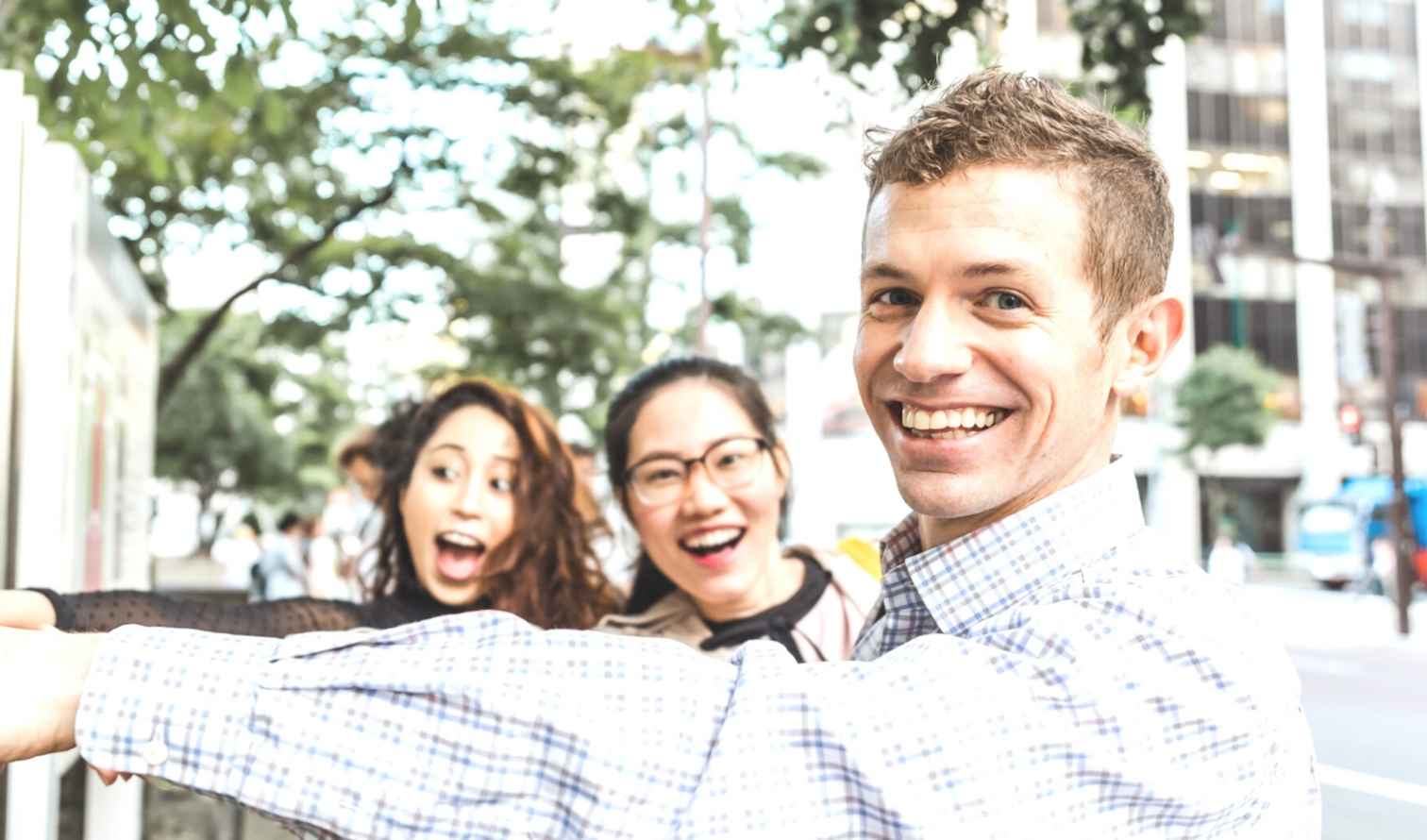 Three people pointing at a map on a street in Sapporo, Japan.