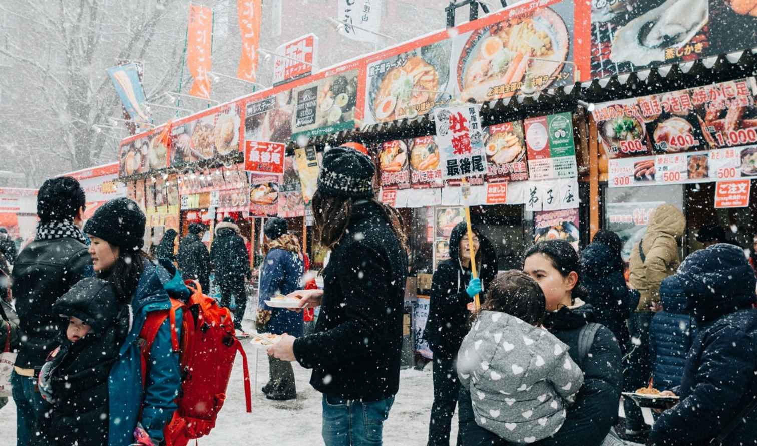 People at an outdoor food market in snowy conditions in Sapporo