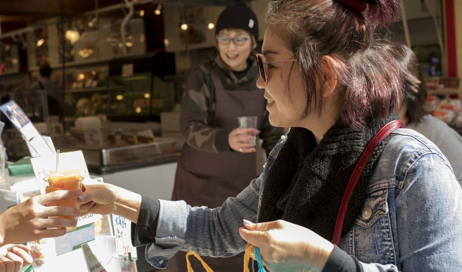 A market vendor hands a drink to a customer in Sapporo