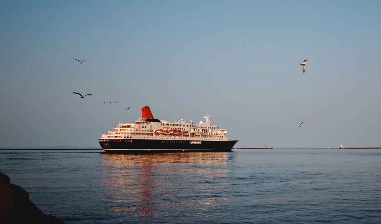 Red-funneled cruise ship passing between piers in Sapporo