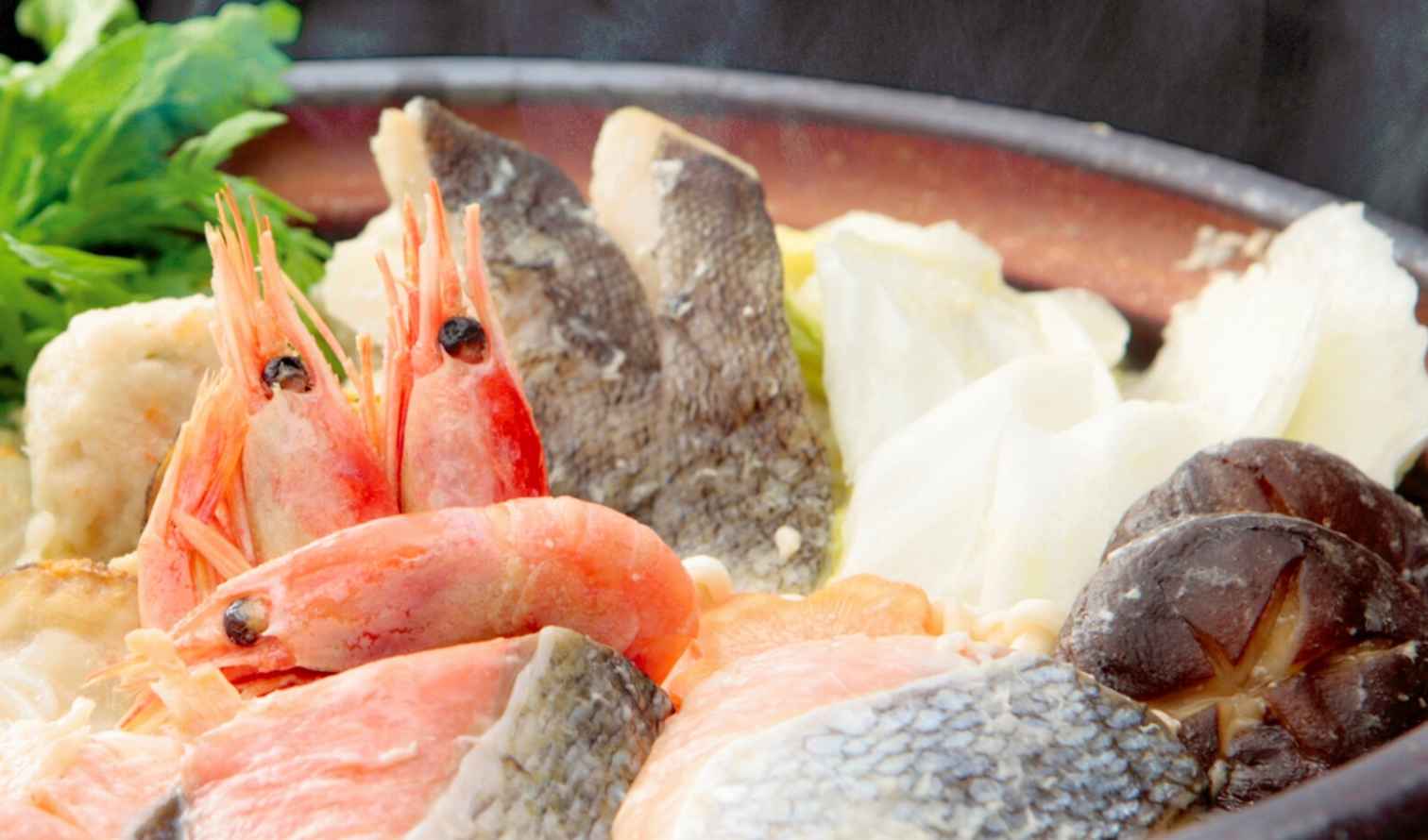 A close-up of a hot pot dish with shrimp, fish, and vegetables in Sapporo