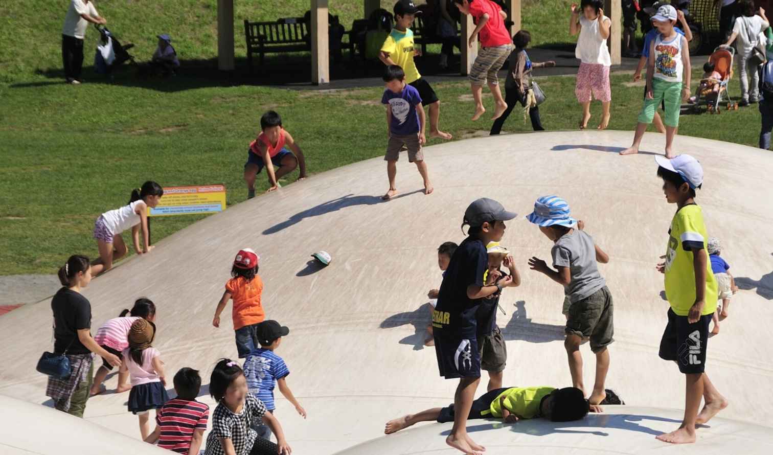 Children playing on a large white inflatable structure in a park in Sapporo