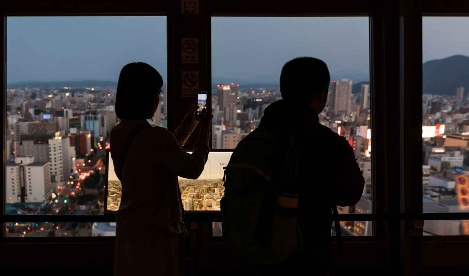 View from Sapporo TV Tower at dusk with people silhouetted.
