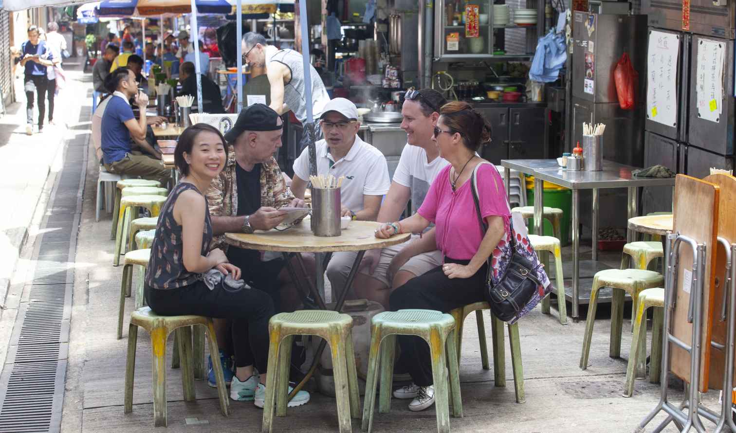 Group dining at an outdoor table in Hong Kong street market.