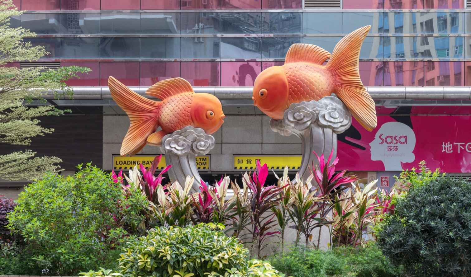 Two large fish sculptures in front of a building in Hong Kong.