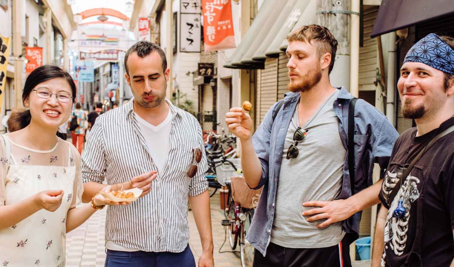 Group of four people standing on a busy street in Japan in Osaka 
