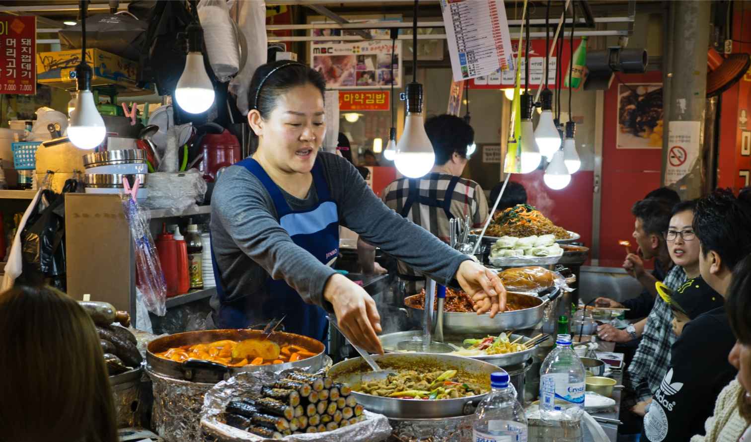 Street food vendor serving dishes at Gwangjang Market in Seoul.