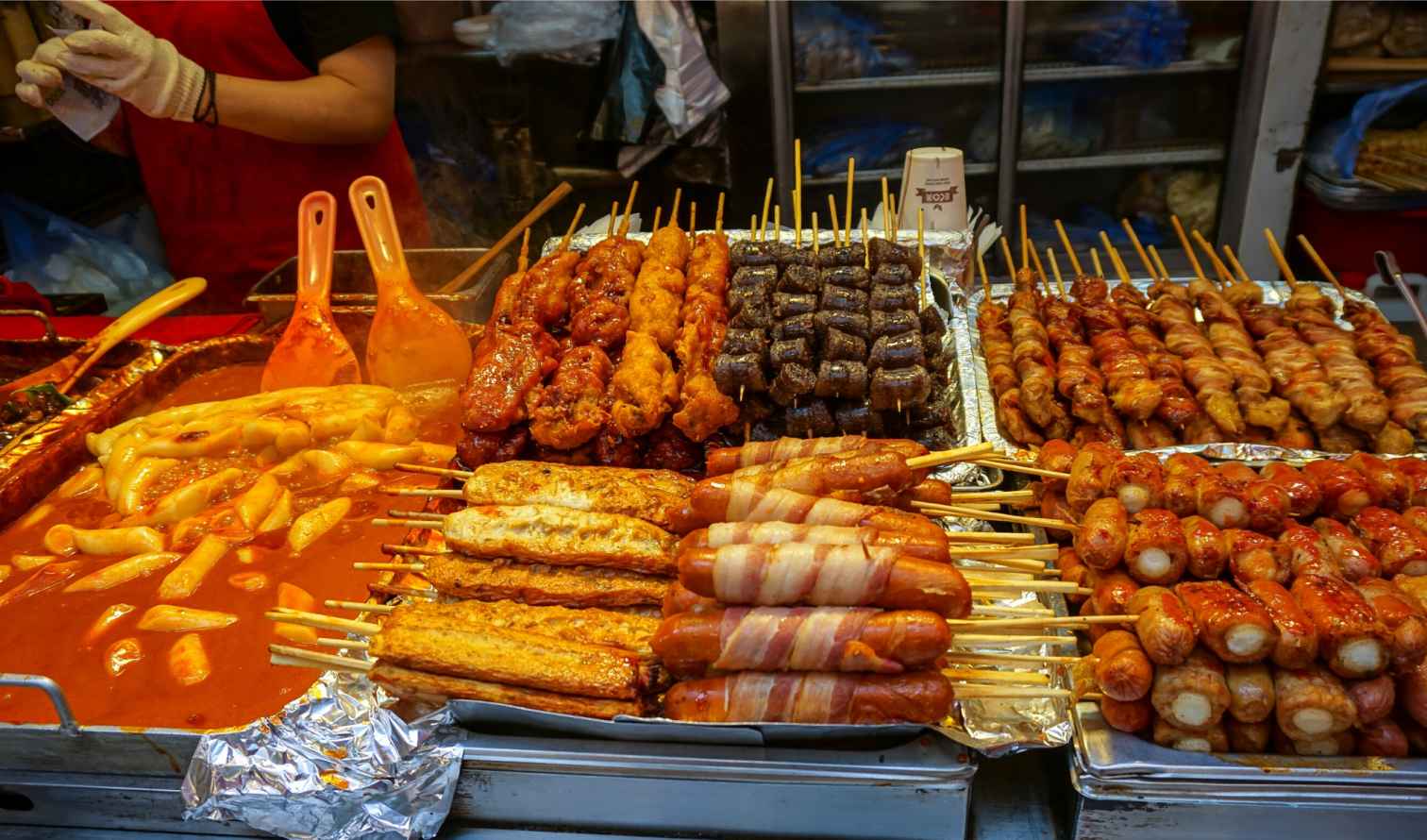 Assortment of grilled skewers and rice cakes at a food market in Seoul.