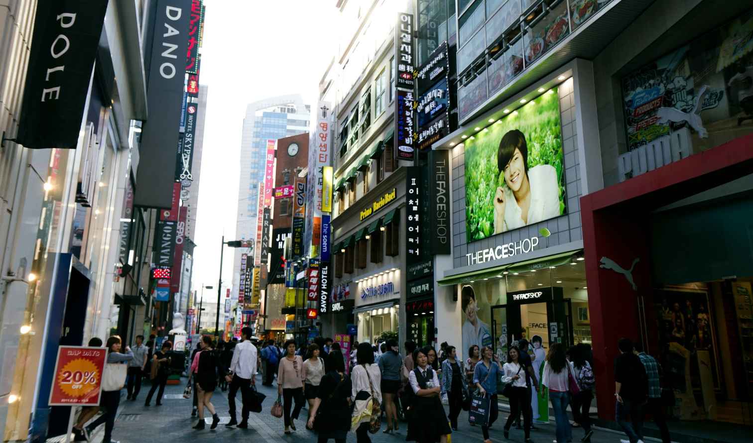 Crowded street in Myeongdong, Seoul with people walking past shops.