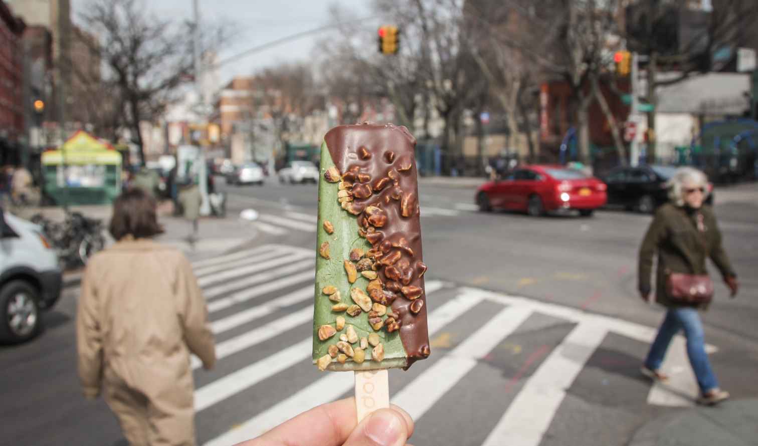 Busy New York City intersection with a person holding an ice cream bar.