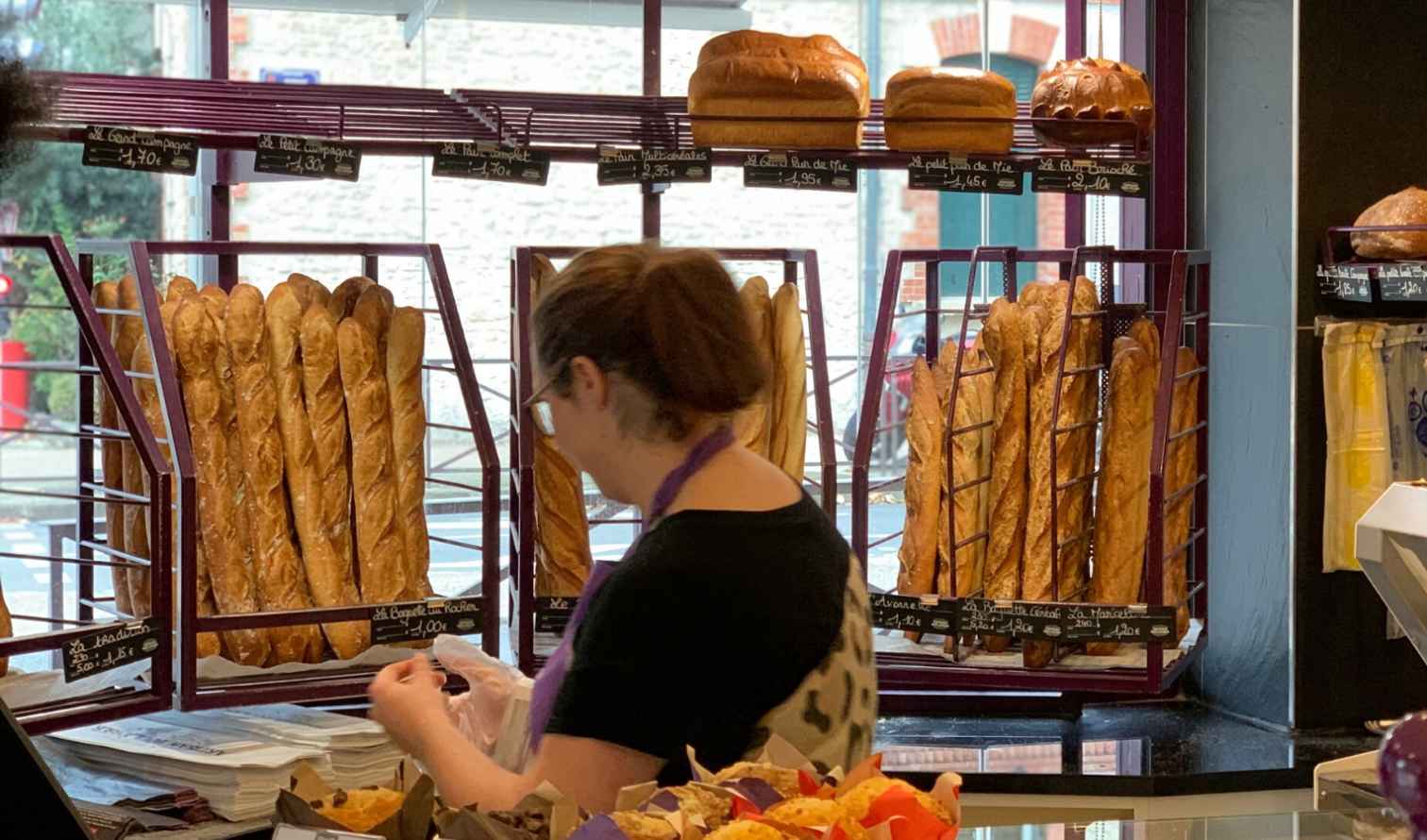 Interior of a bakery with baguettes on display racks in Paris