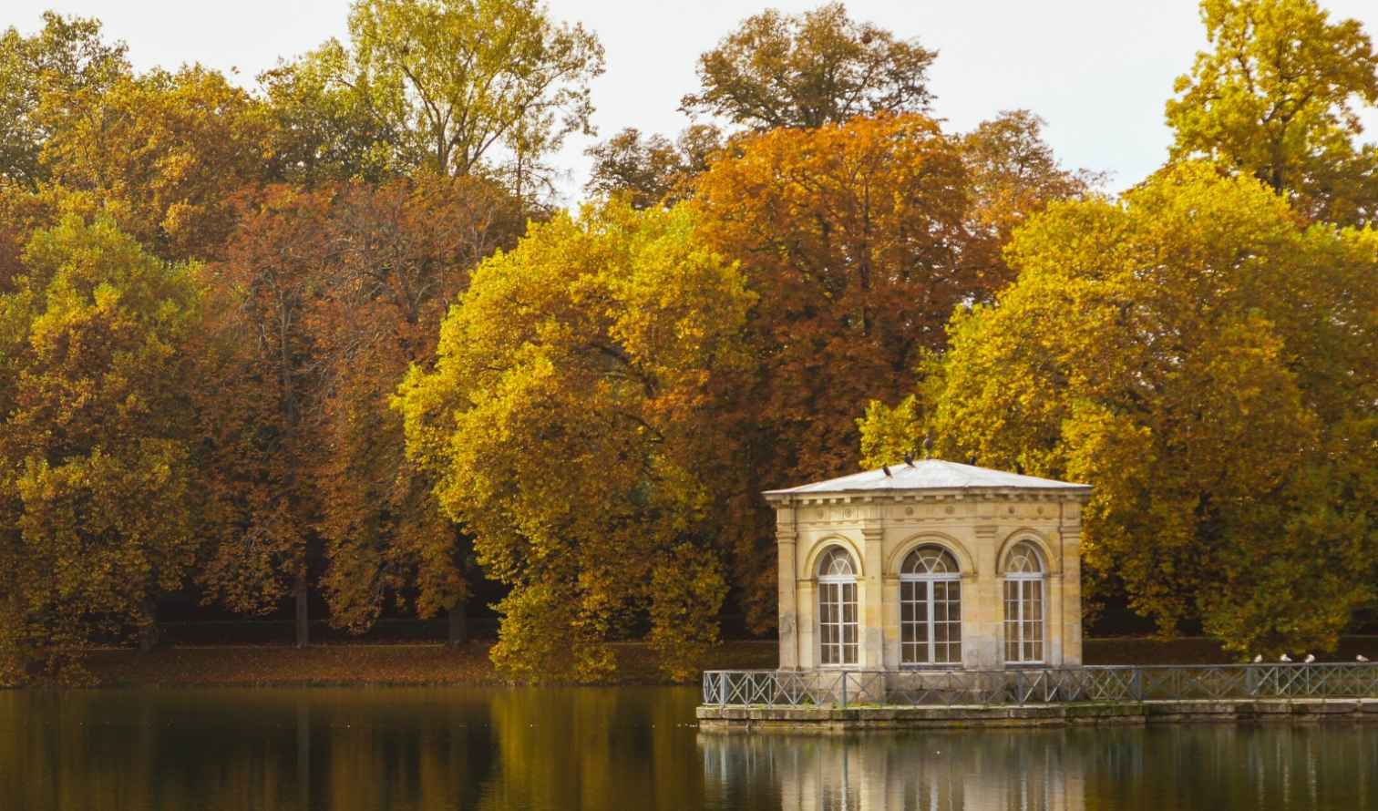 Small pavilion at the edge of a lake in a park with autumn trees in Paris