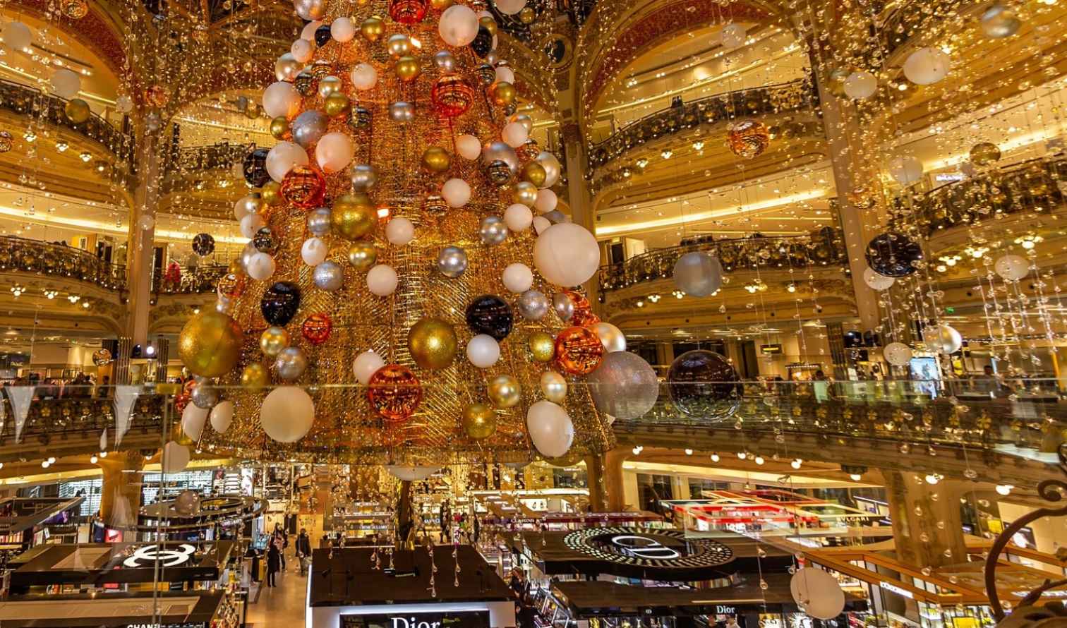 Shoppers visible under a giant Christmas tree in Galeries Lafayette, Paris.