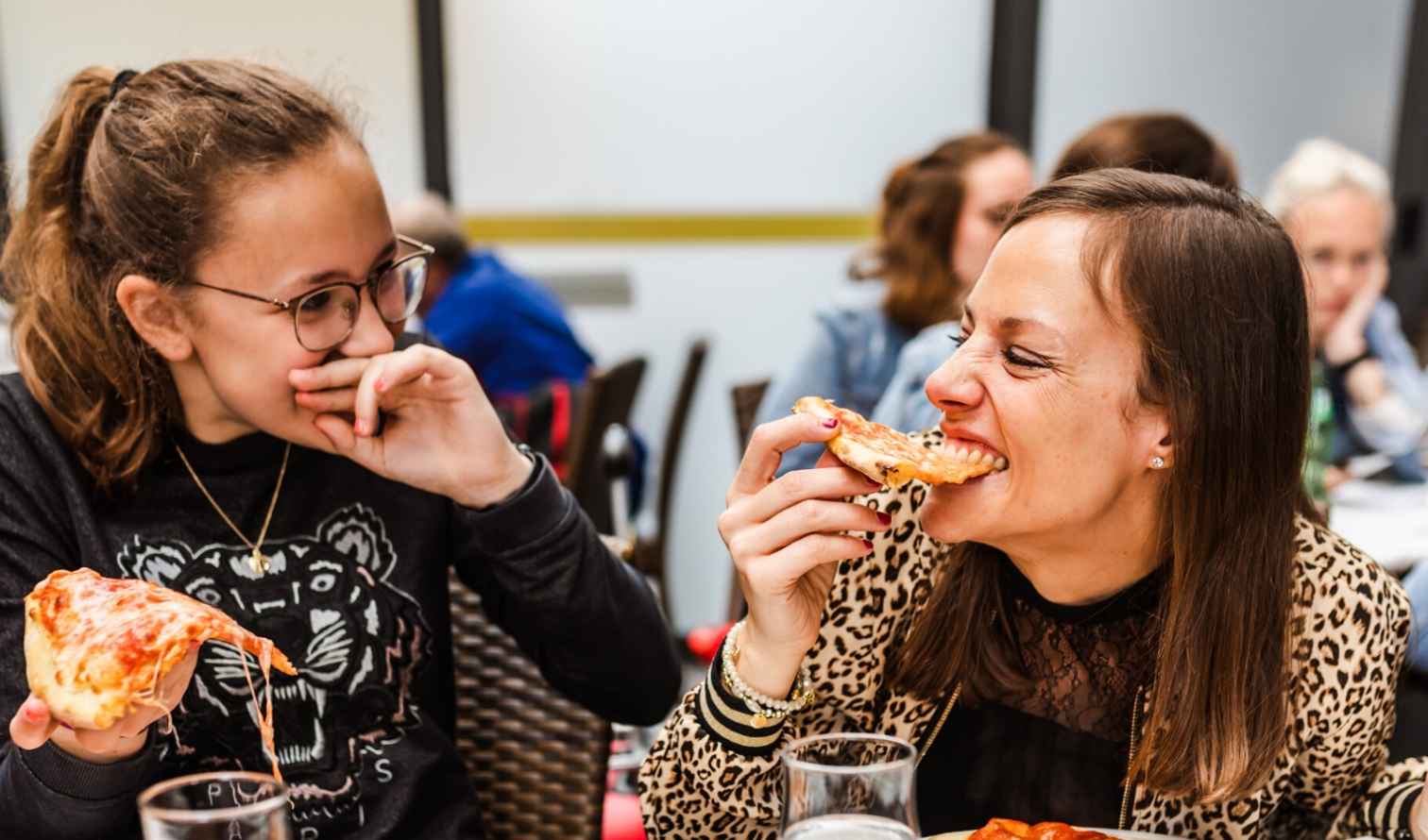 Two people eating pizza at a restaurant indoors in Milan