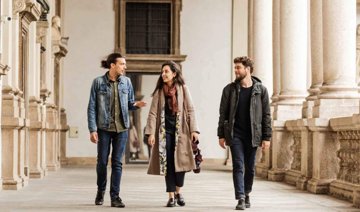 Three people walking through a columned corridor at Palazzo Brera, Milan.