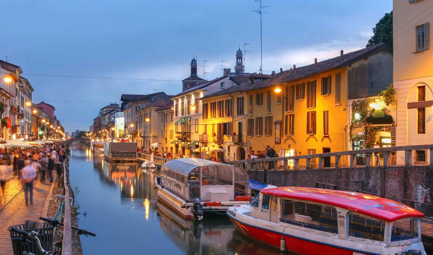 Canal with boats in the Navigli district of Milan at dusk.