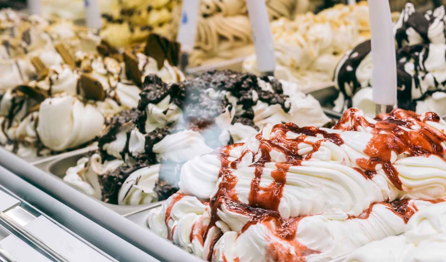 Close-up of various gelato flavors with chocolate and fruit toppings in Milan