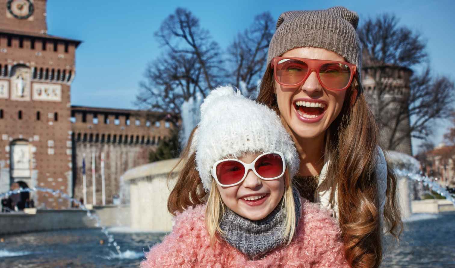 Two people wearing sunglasses in front of Castello Sforzesco, Milan.