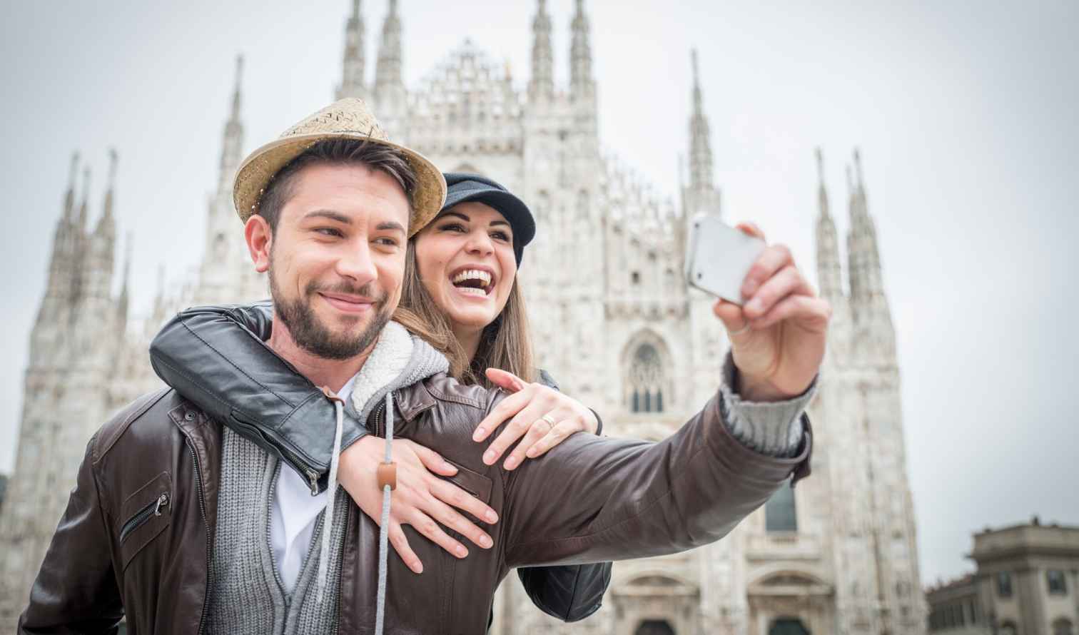 Couple taking a selfie in front of Milan Cathedral.