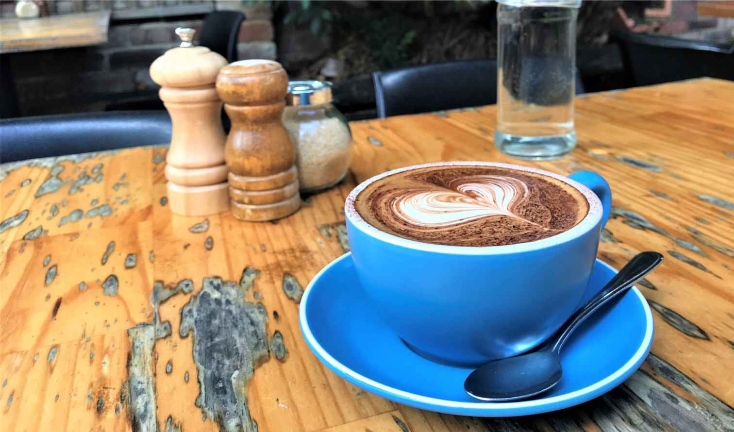Blue coffee cup with latte art on a wooden table in Sydney