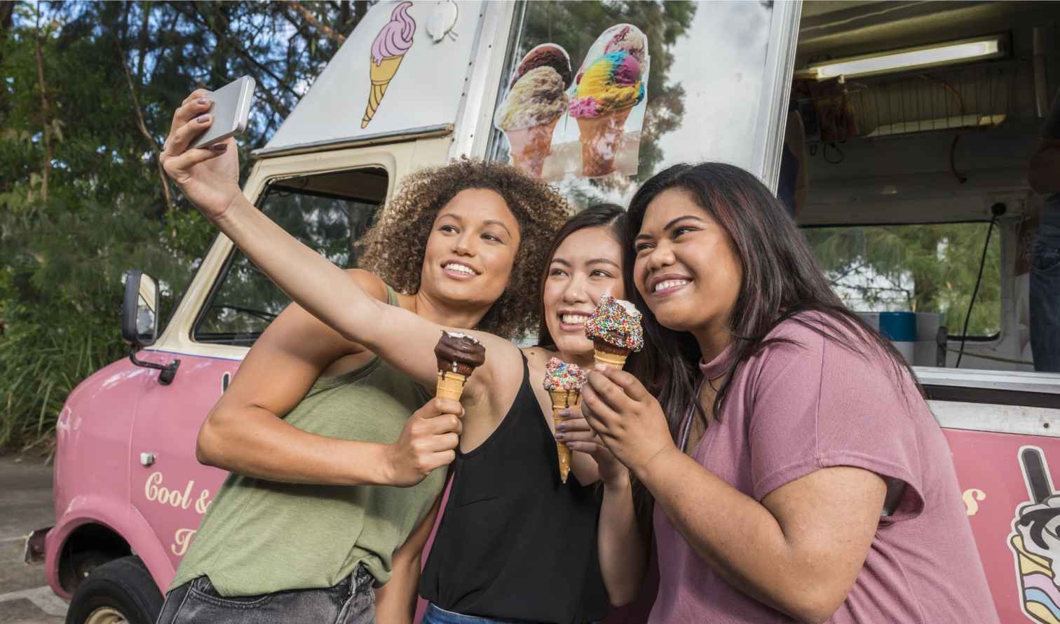 Three women taking a selfie in front of a pink ice cream truck in Sydney