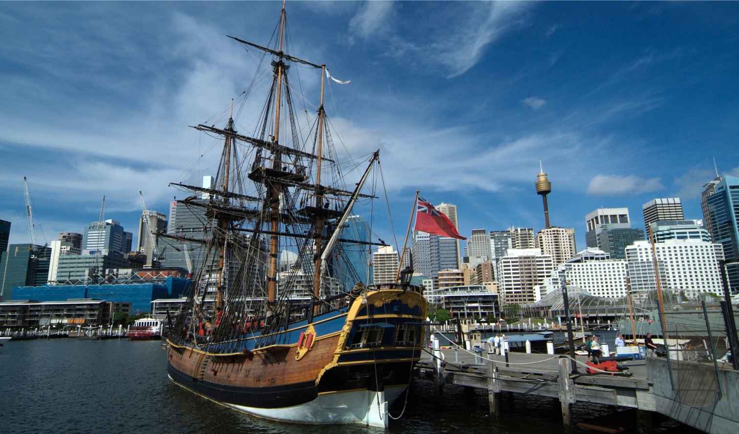 Historic ship docked at Darling Harbour with Sydney skyline in the background.