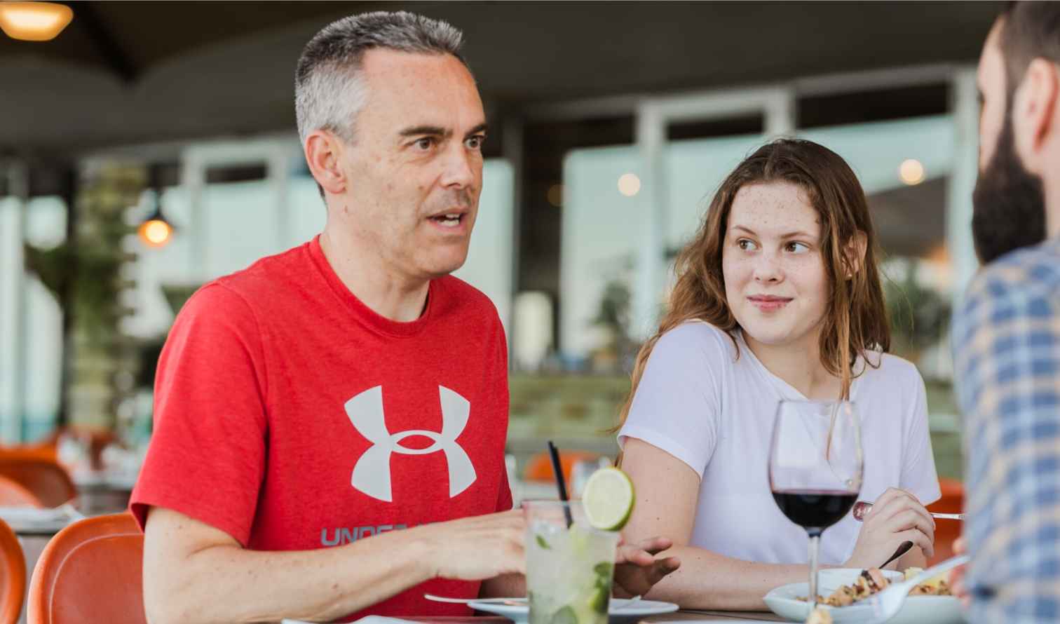 People seated at an outdoor restaurant table with drinks and food in Barcelona.