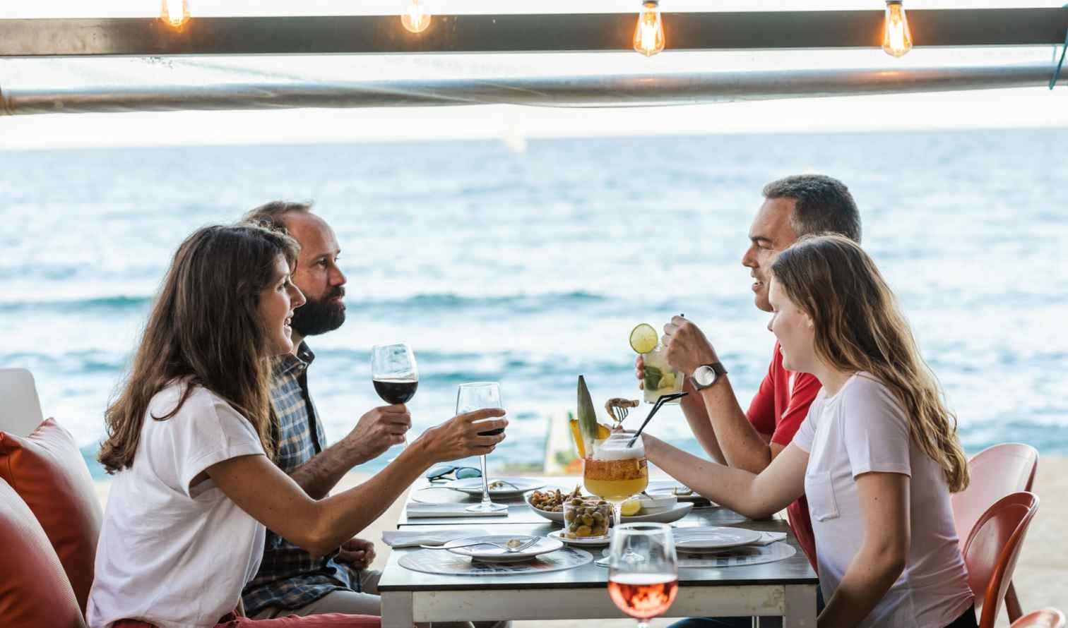 Four people having drinks at a beachside restaurant in Barcelona.