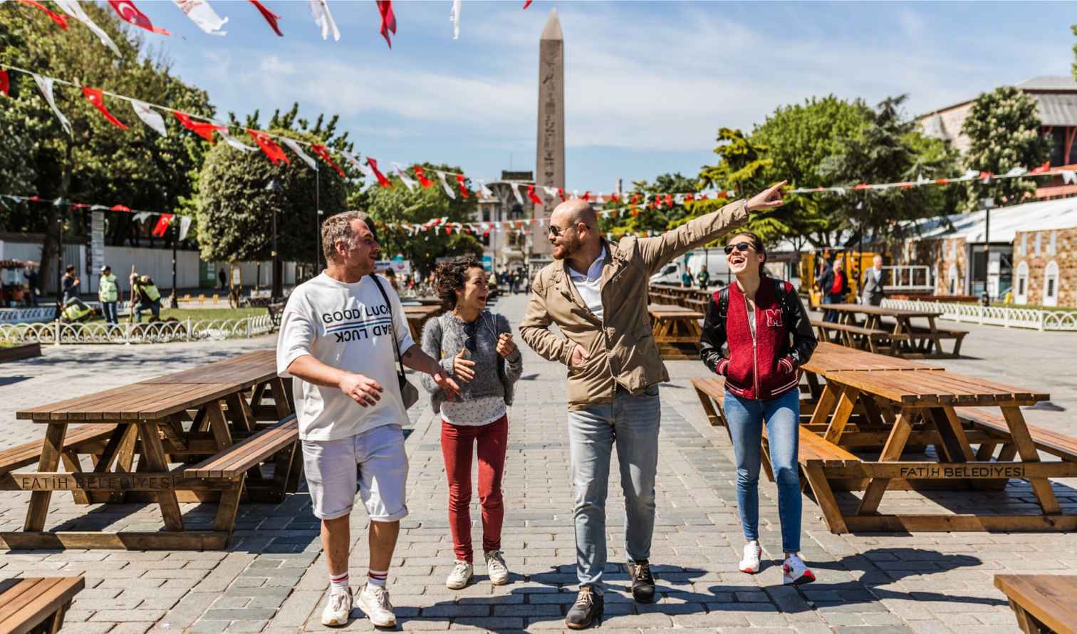 Four people walking near the Obelisk of Theodosius in Istanbul.