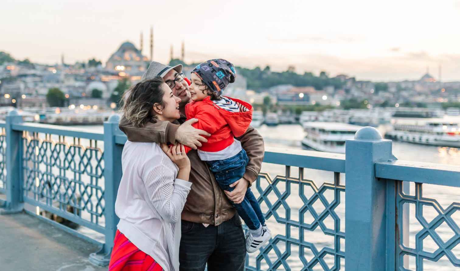 Family standing on Galata Bridge in Istanbul with mosques in the background.
